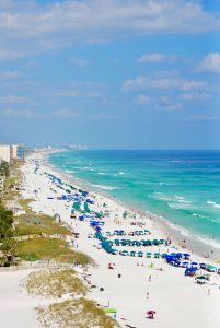 Aerial view of a busy white-sand beach and turquoise ocean – Delray Beach vs Boca Raton
